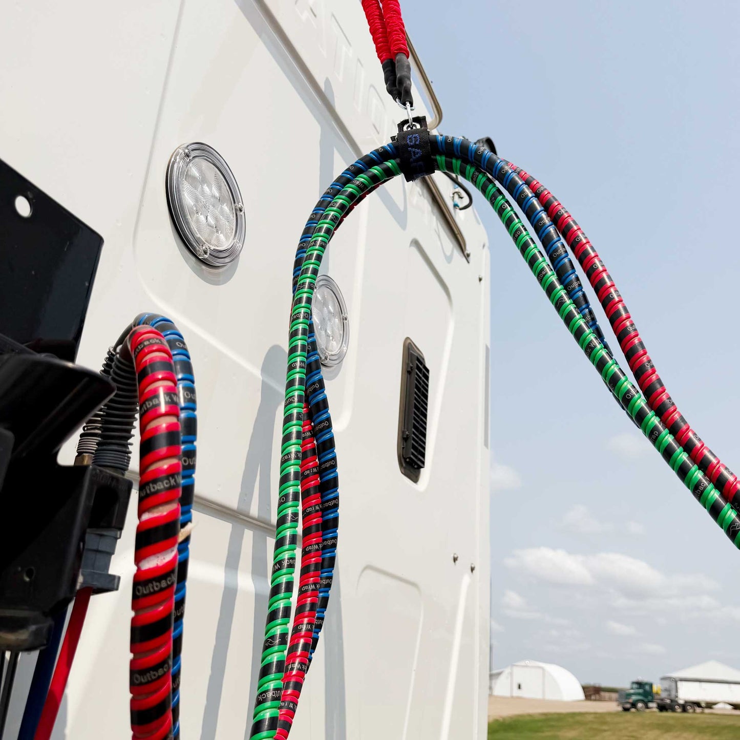 Protected semi truck air lines and semi truck trailer air lines organized with Outback Wrap spiral wraps and hose management accessories between tractor and trailer.