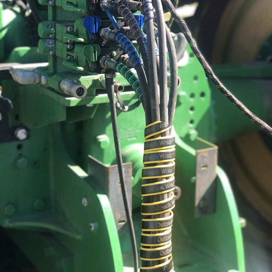 Hydraulic hose tamer, in yellow, holding 6 hydraulic hoses in a group