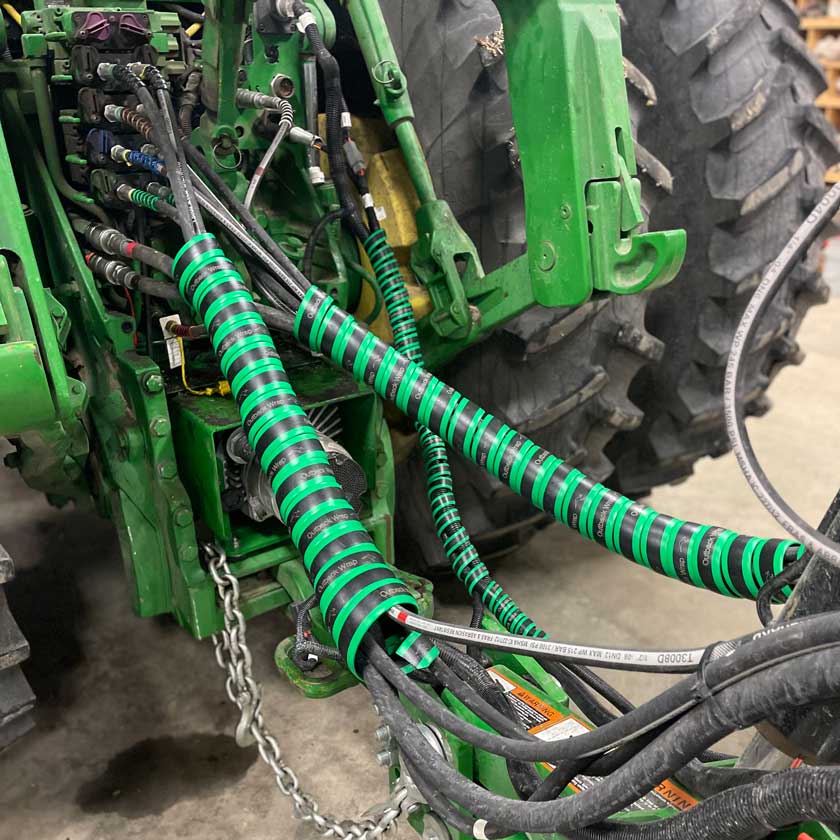 Green hose bosses protecting the hydraulic hoses on a John Deere planter.