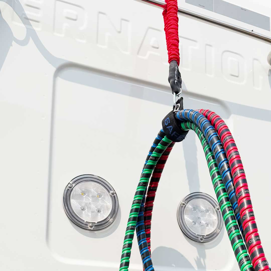 A close up of the Outback Wrap Stretchy Strap and the Outback Wrap Bat Wrap bundling and lifting the air line hoses on a semi truck.