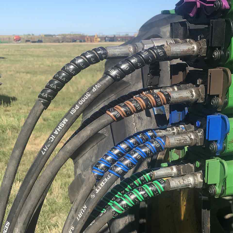 The Outback Wrap 4-pack of hydraulic hose color markers on a tractor in a field.